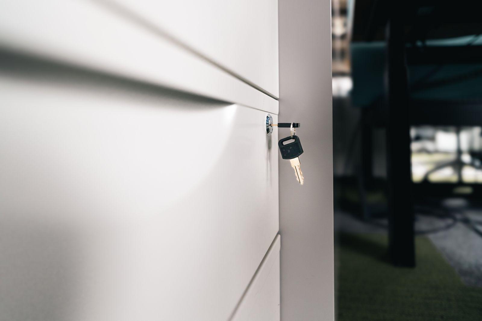 Clé insérée dans la serrure d'un meuble de bureau blanc, symbole d'un accès verrouillé et sécurisé