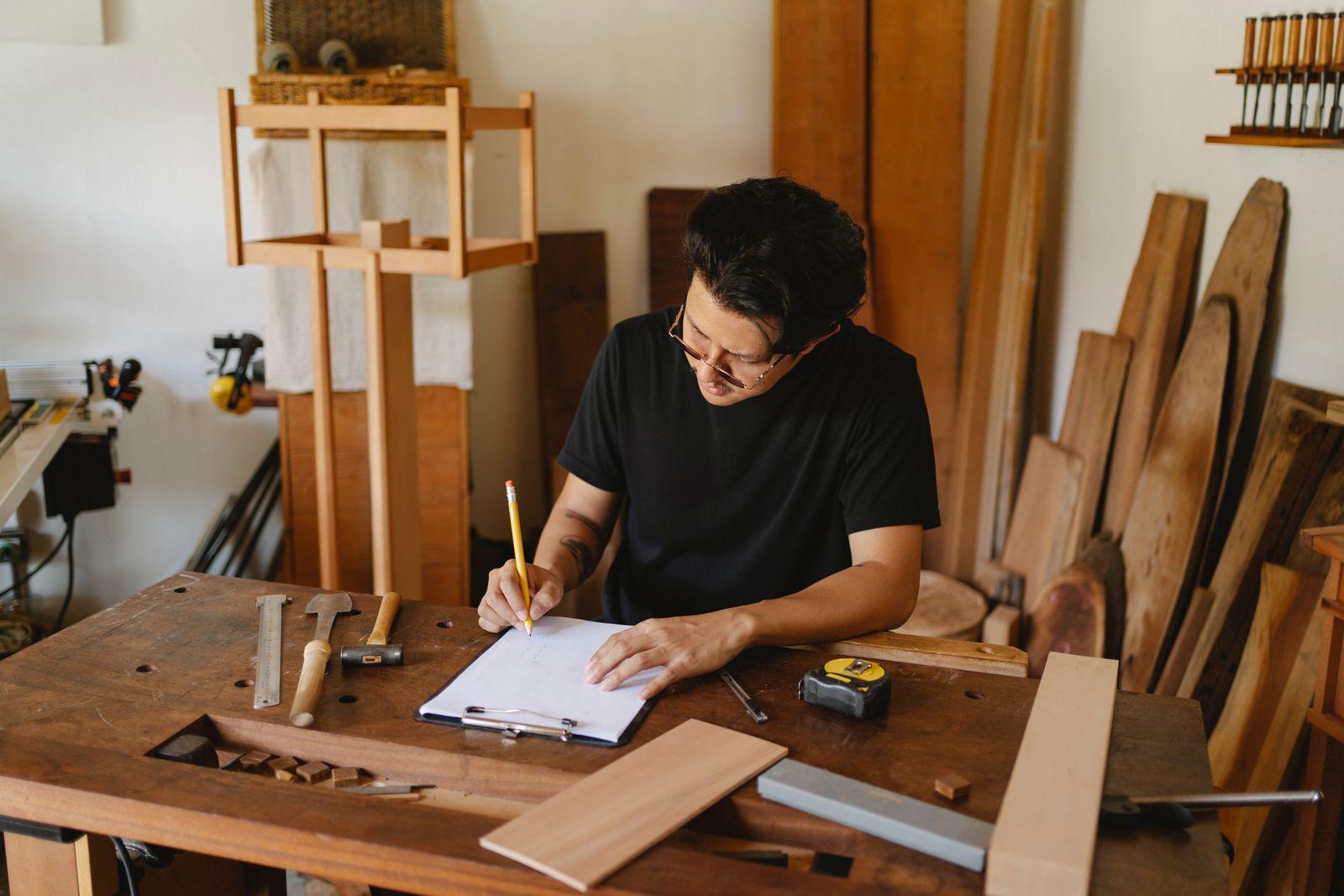 Un artisan menuisier prend des notes sur un carnet dans son atelier