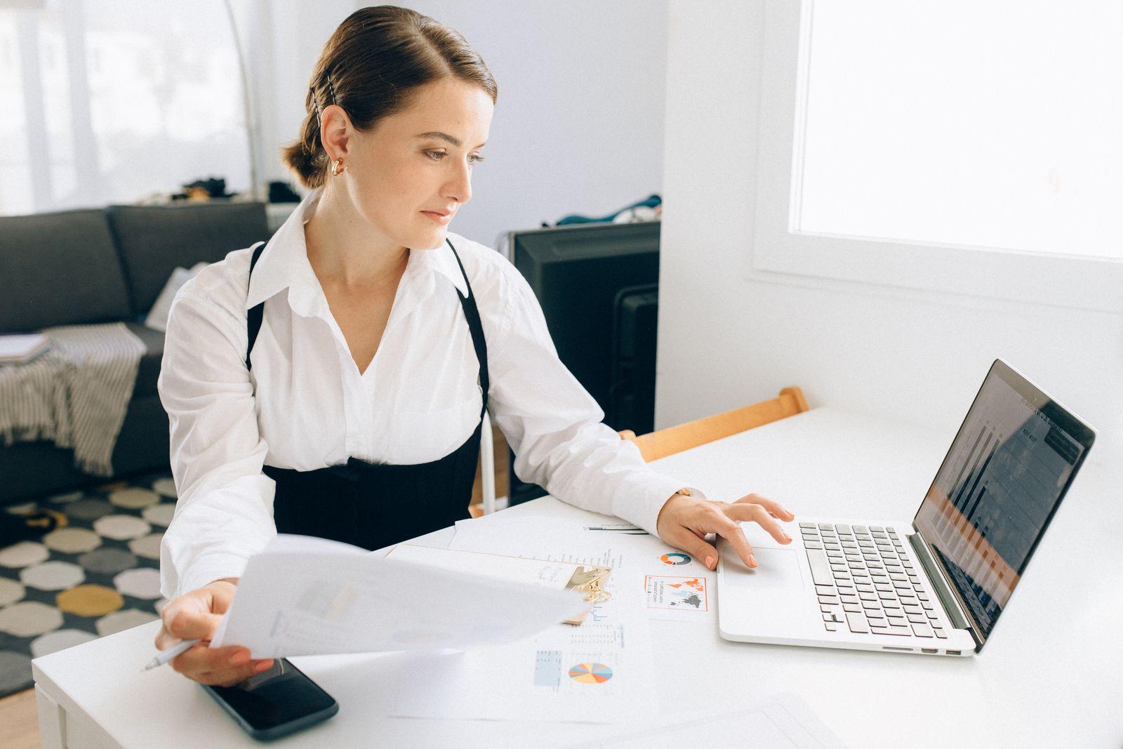 Une professionnelle analyse des documents et graphiques sur son ordinateur portable