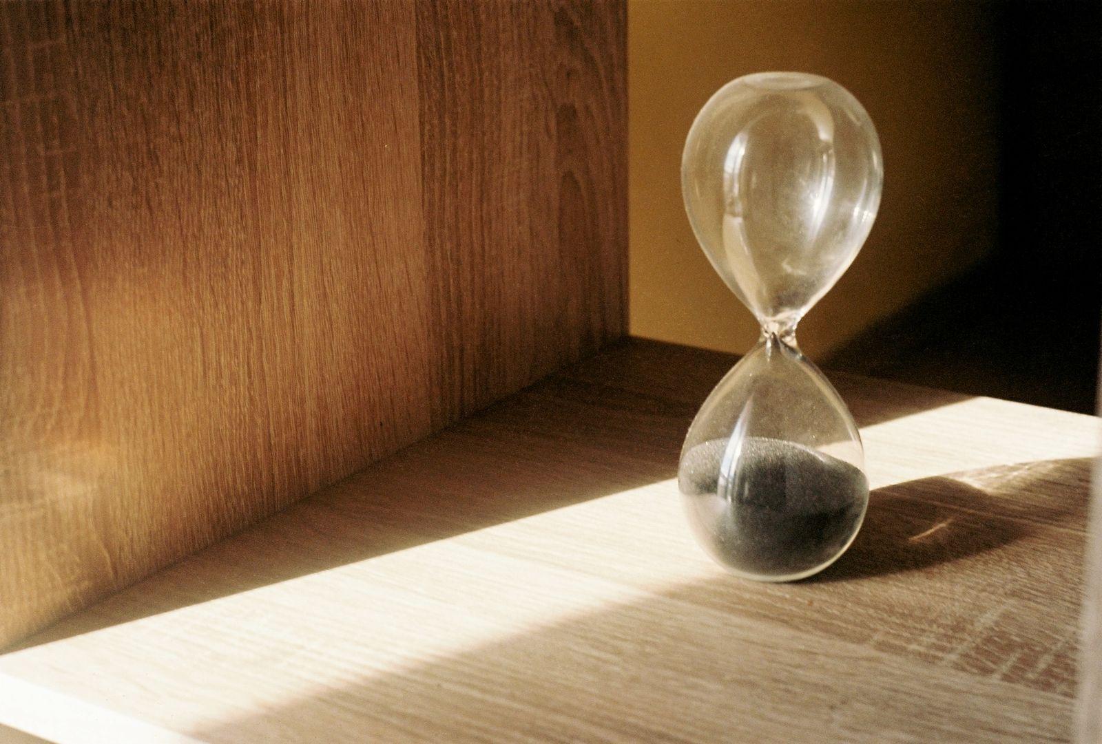 Sablier posé sur une étagère en bois, symbole du temps qui passe