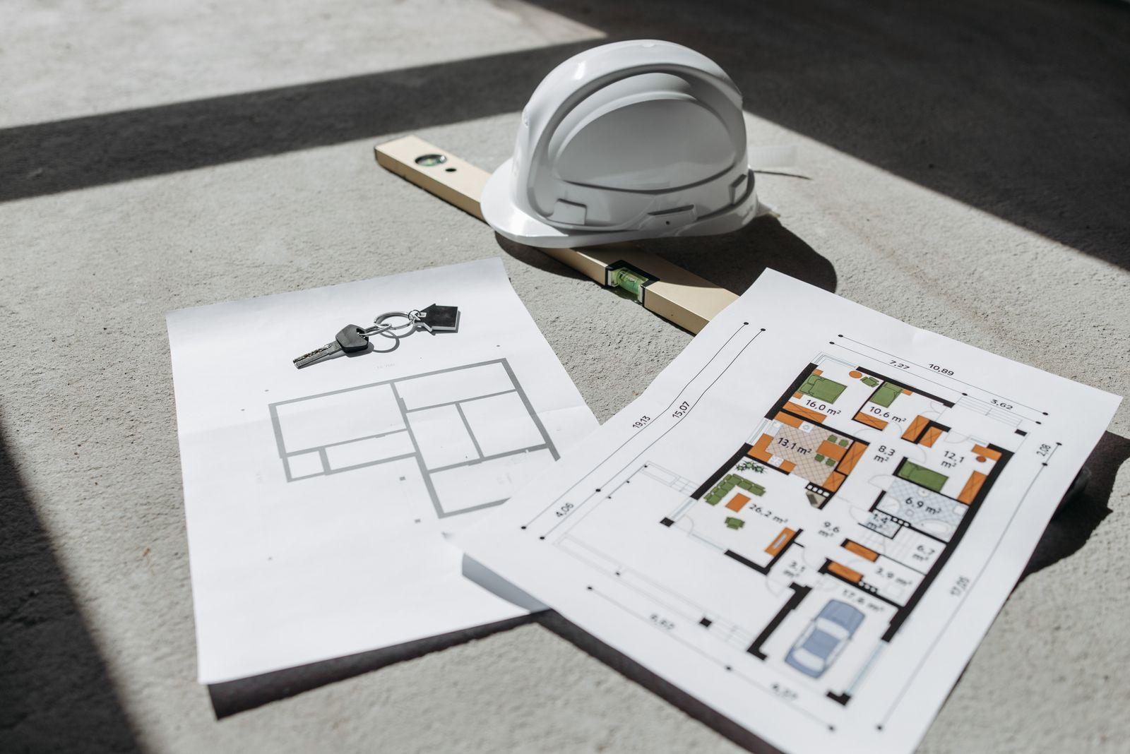 Casque de chantier et niveau à bulle posés sur des plans de construction