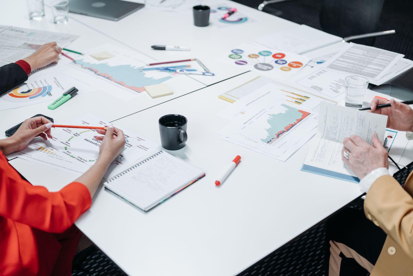 Deux personnes travaillant ensemble sur des documents et graphiques étalés sur une table de bureau