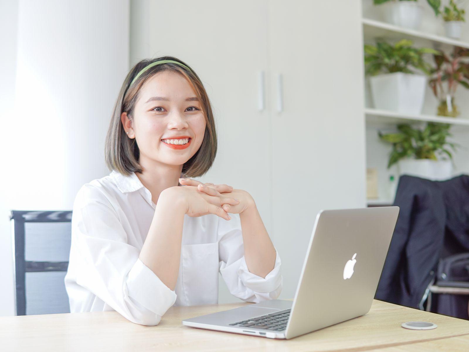 Femme souriante assise à son bureau avec un ordinateur portable ouvert devant elle
