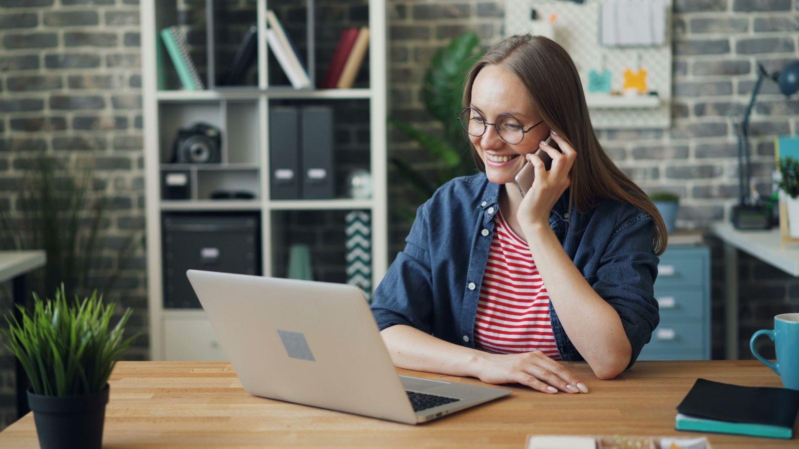 Femme au téléphone devant son ordinateur portable dans un bureau