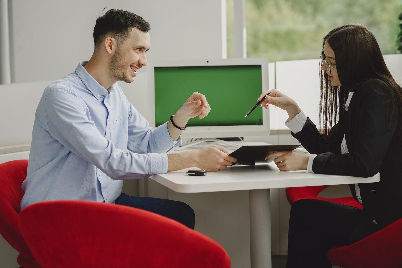 Un homme et une femme discutant autour d'un bureau dans un espace de travail moderne, un dossier à la main