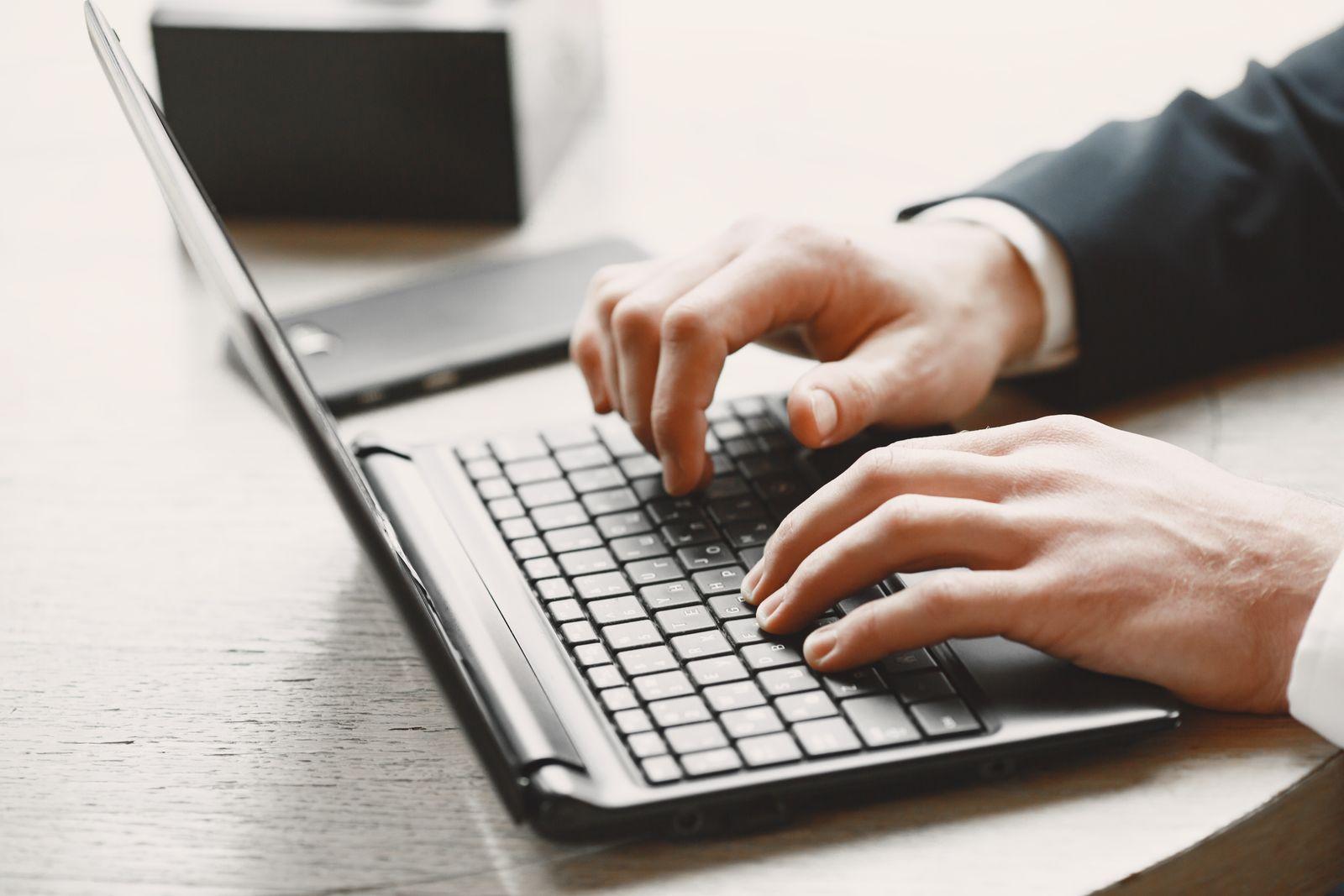 Gros plan sur des mains tapant sur le clavier d'un ordinateur portable dans un cadre professionnel épuré