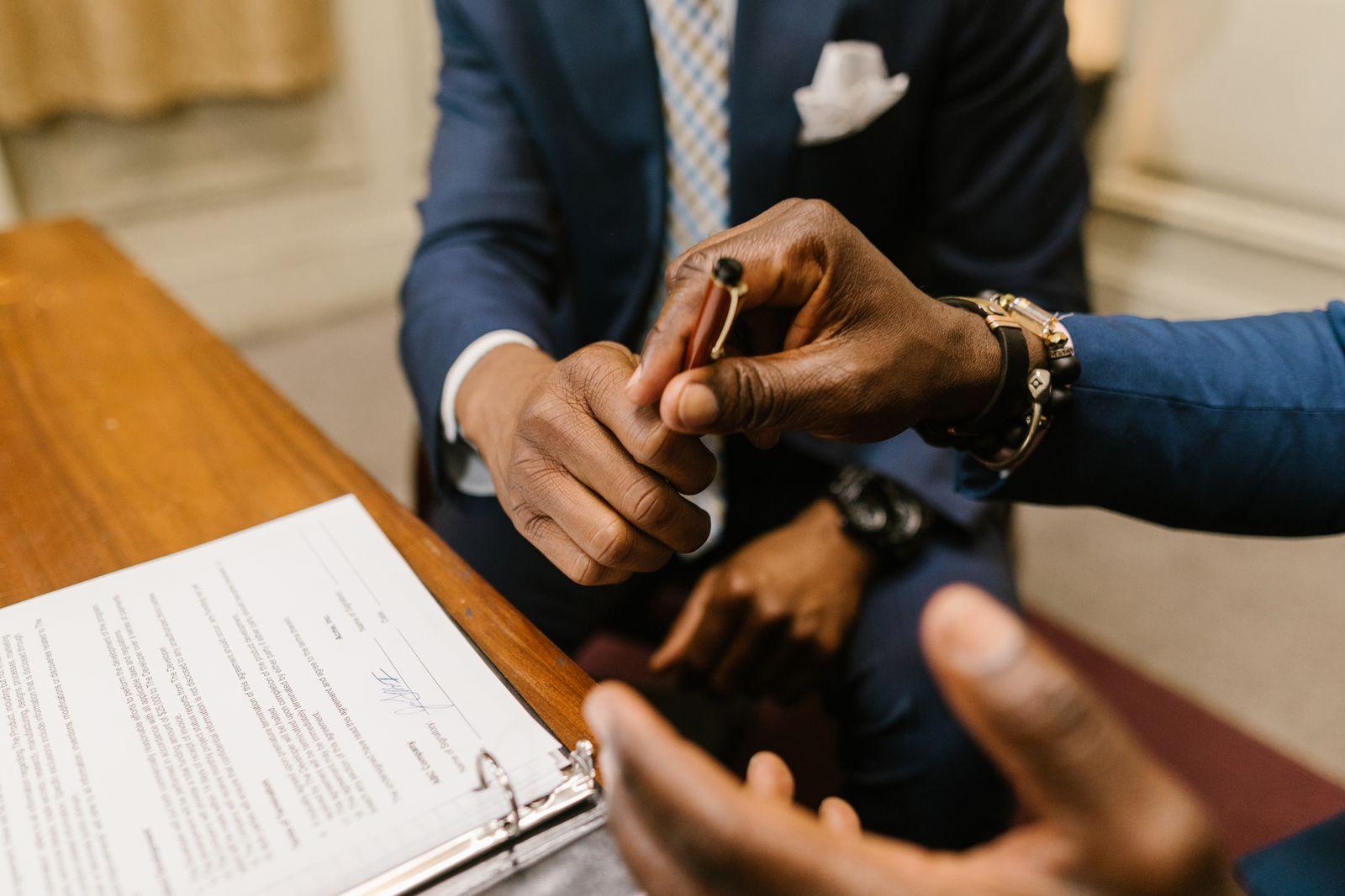 Un client signe un document remis par un conseiller en costume dans un bureau