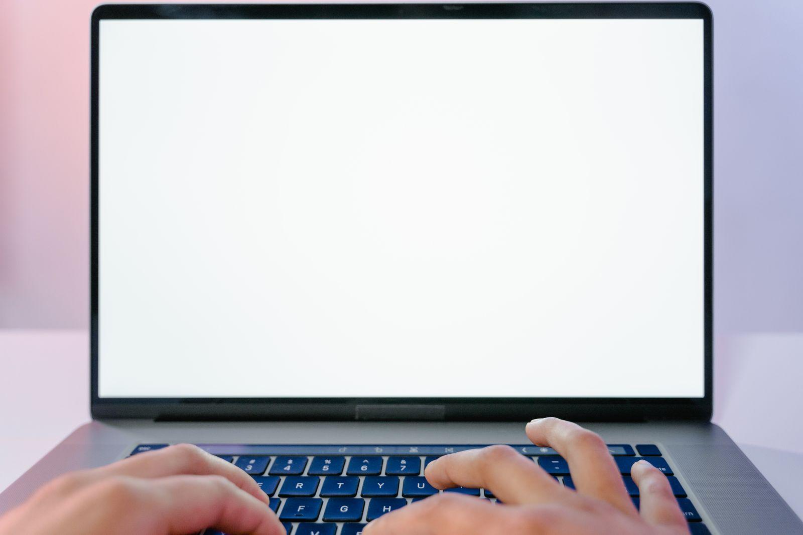 Mains tapant sur le clavier d'un ordinateur portable face à un écran clair