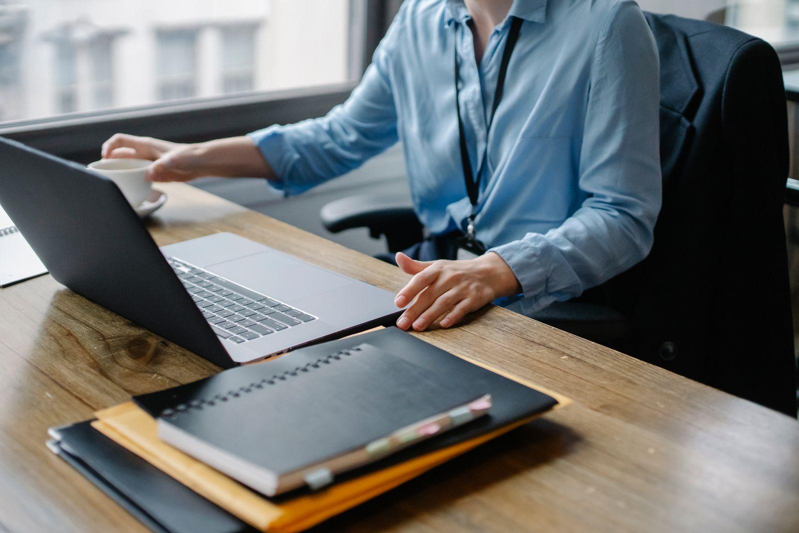 Professionnelle au bureau avec ordinateur portable, dossiers et tasse de café