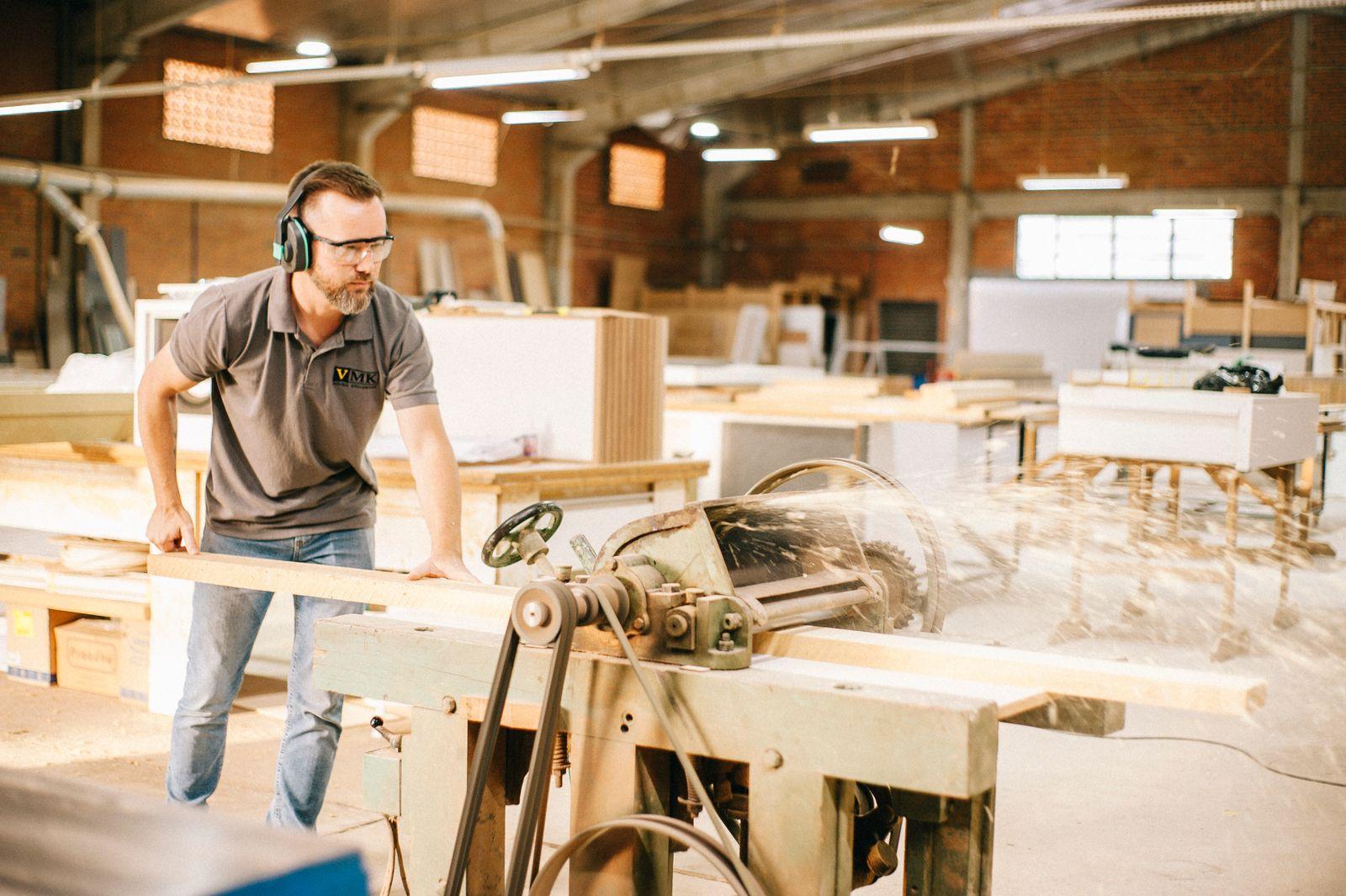 Artisan menuisier travaillant une pièce de bois sur une machine dans son atelier