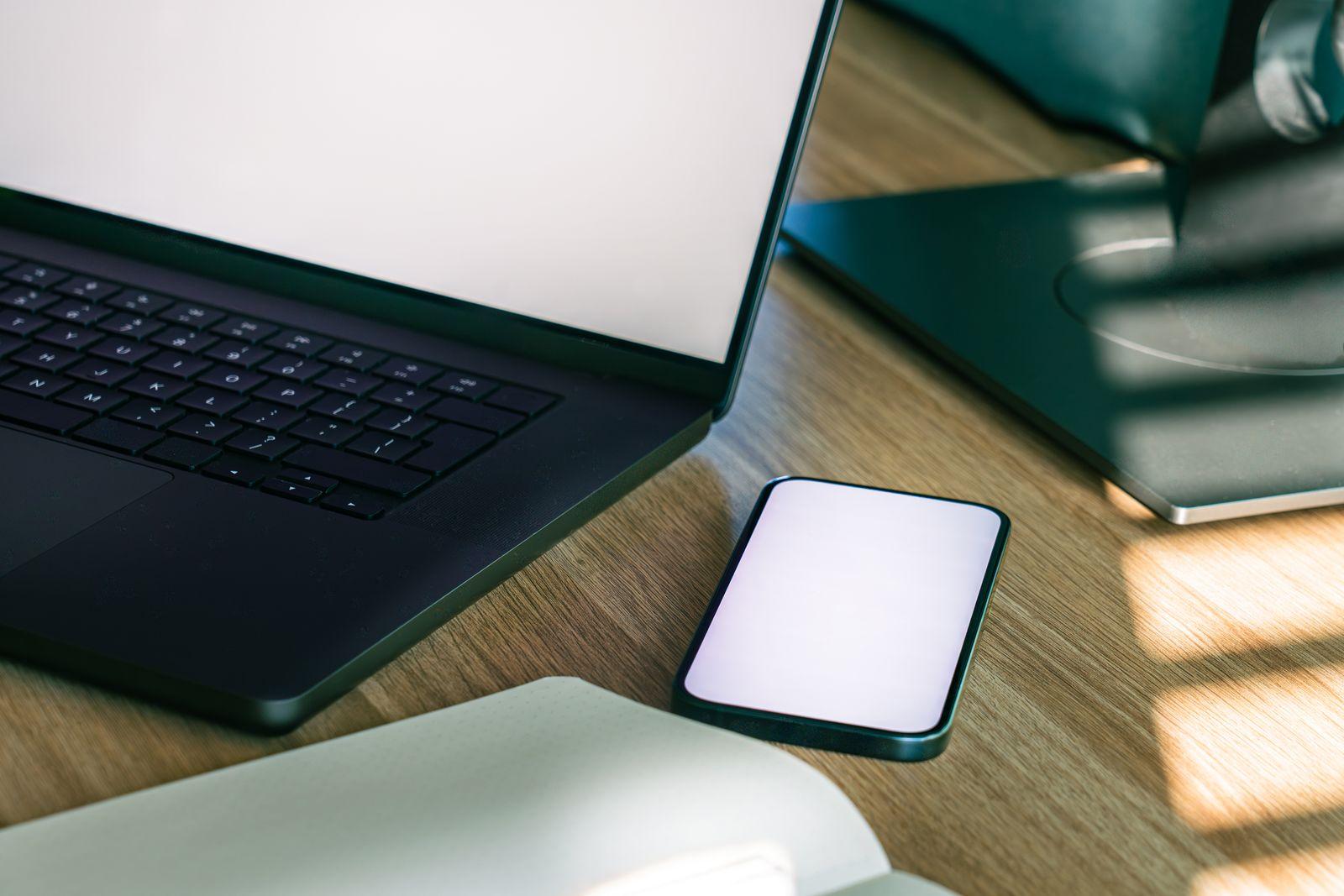 Ordinateur portable et smartphone posés sur un bureau en bois