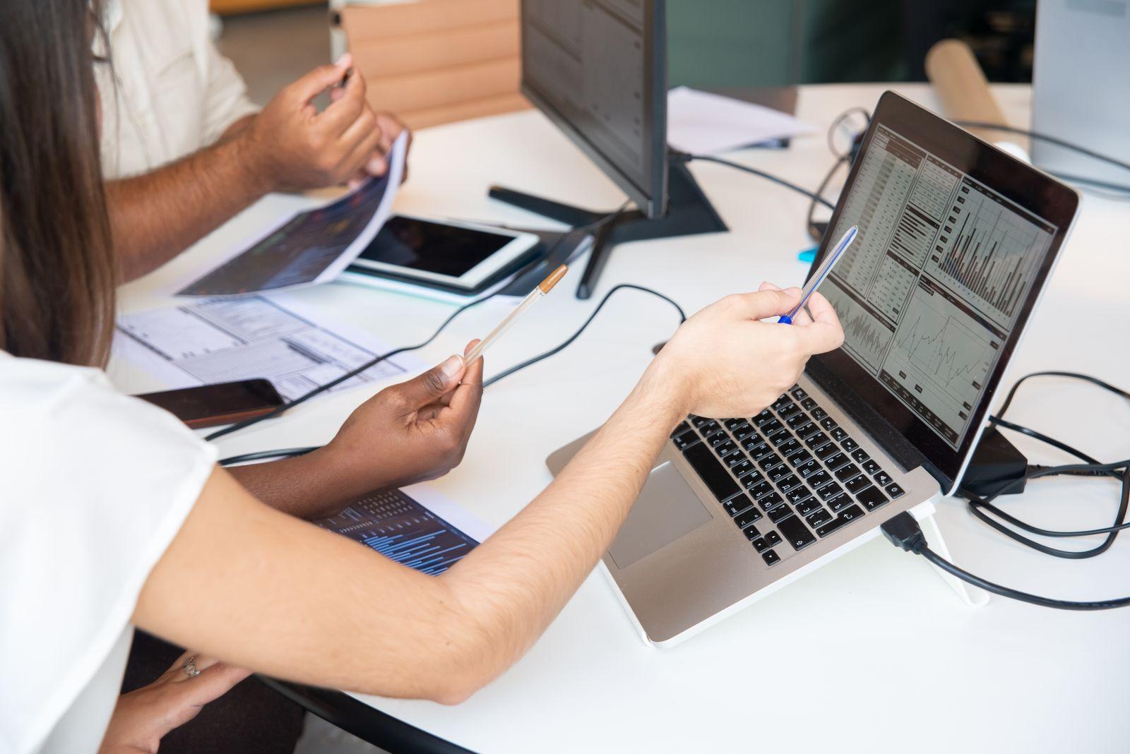 Deux personnes analysant des graphiques financiers sur un ordinateur portable