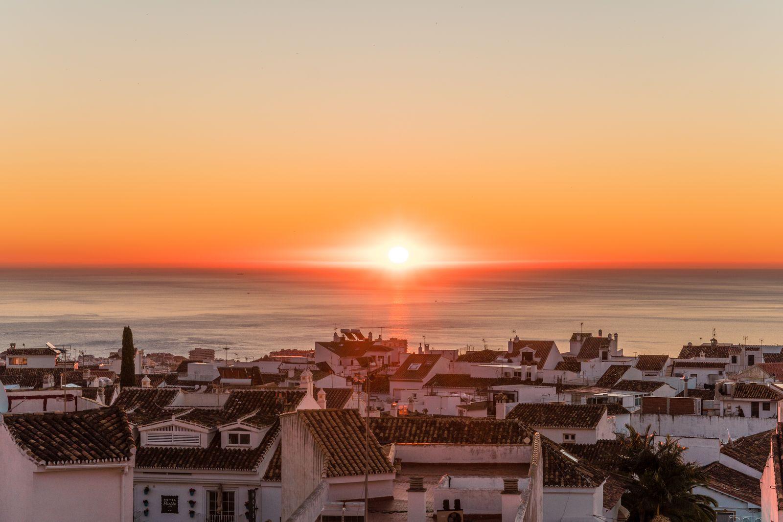 Vue d'une petite ville côtière au coucher de soleil, avec toits et front de mer