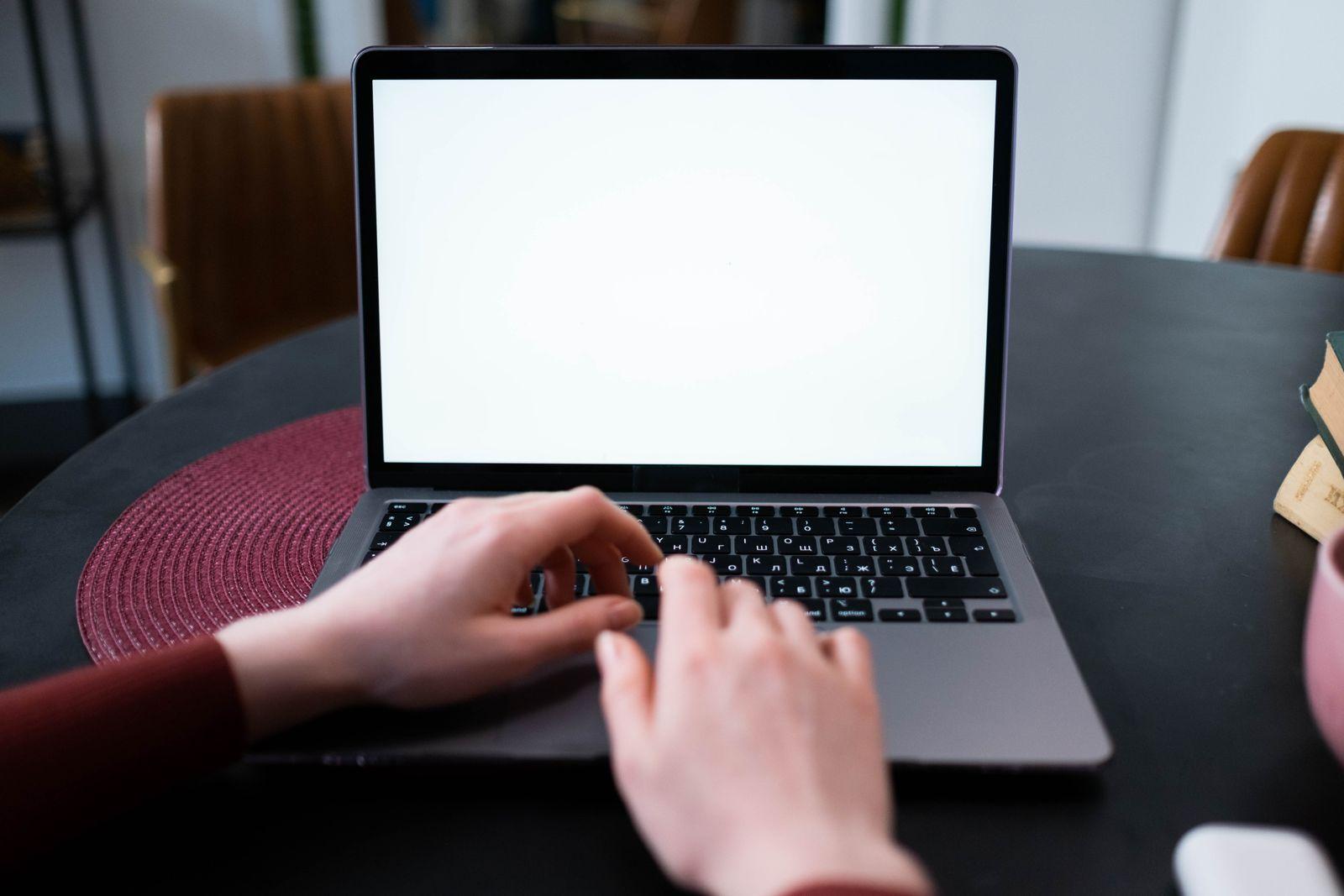 Mains sur le clavier d'un ordinateur portable ouvert sur un bureau